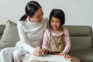 Smiling woman tutoring ethnic girl at home